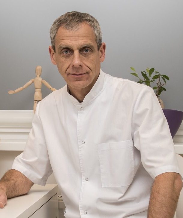 Gydytojas osteopatas Nikolajus Lobanovas baltu chalatu savo kabinete